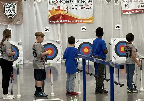 Row of school children competing in archery tournament.