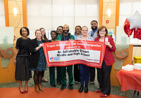 Superintenden Michele Mitchell with Achievable Dream personnel holding a sign about being designated a heart safe school.